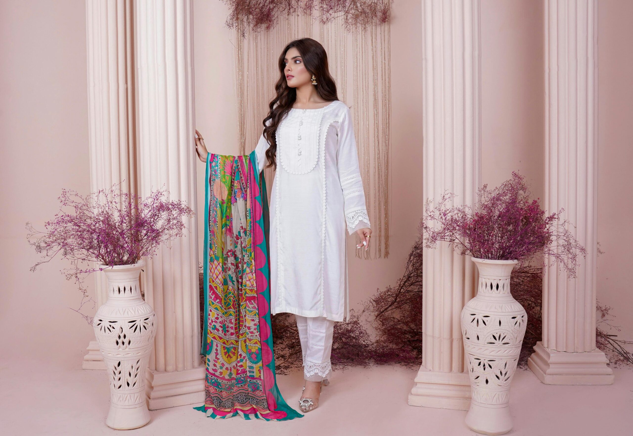 A stylish woman in traditional South Asian attire poses gracefully indoors.